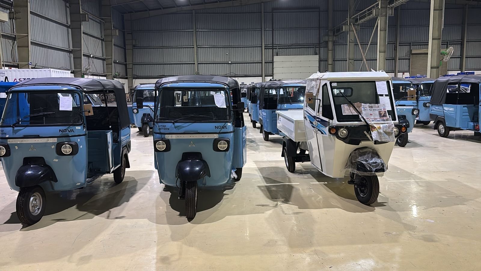 A line of blue passenger three-wheelers, the Nova, inside the factory