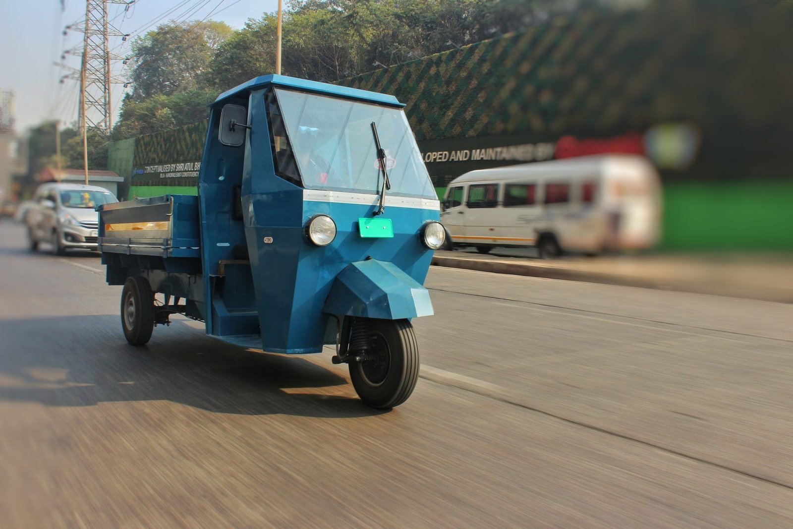Blue Navya pilot vehicle driving past on a city road, side view